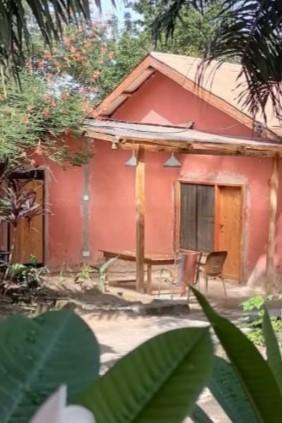 An inviting pink house exterior with custom wooden doors and a wooden porch table and chairs, all made by Star construction
