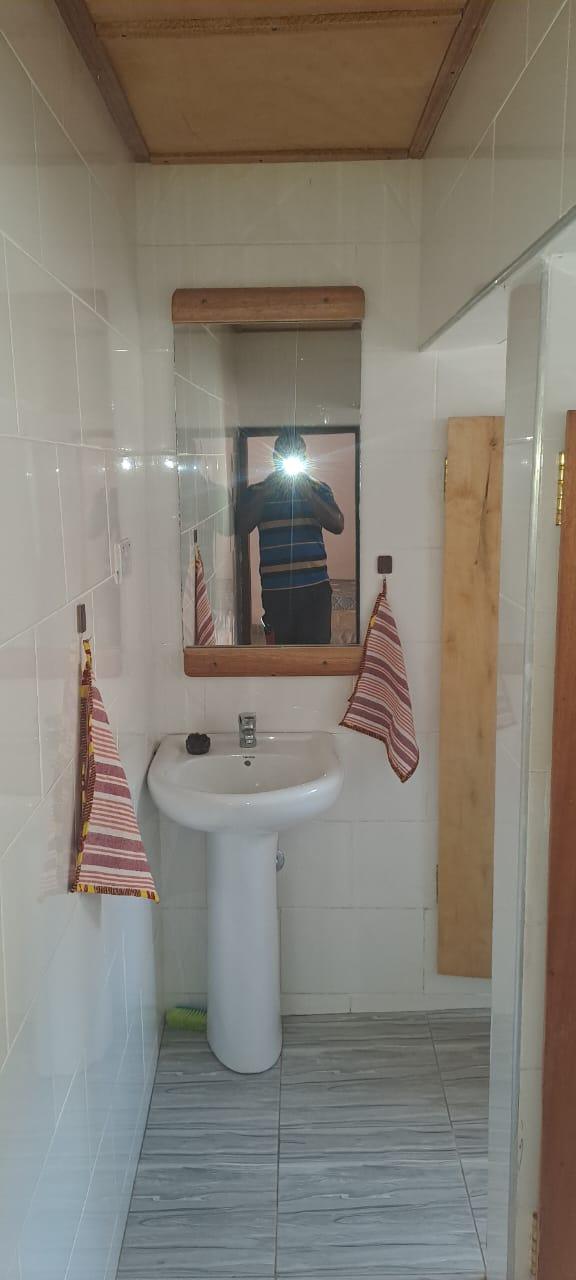 A bathroom mirror with a custom wooden frame, positioned above a white pedestal sink.
